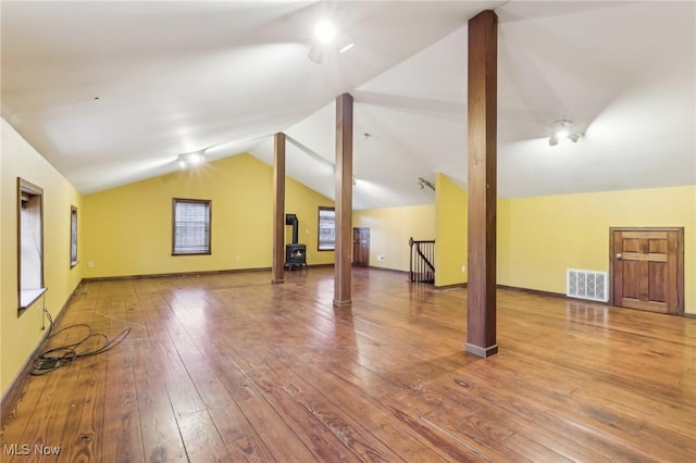 interior space featuring hardwood / wood-style flooring, baseboards, visible vents, and vaulted ceiling