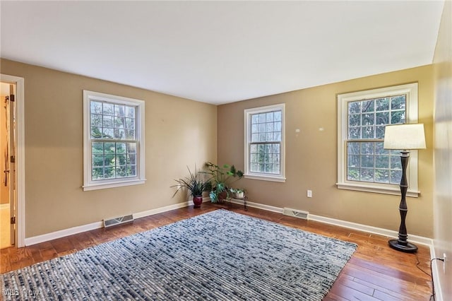 living area featuring hardwood / wood-style floors, visible vents, and a wealth of natural light