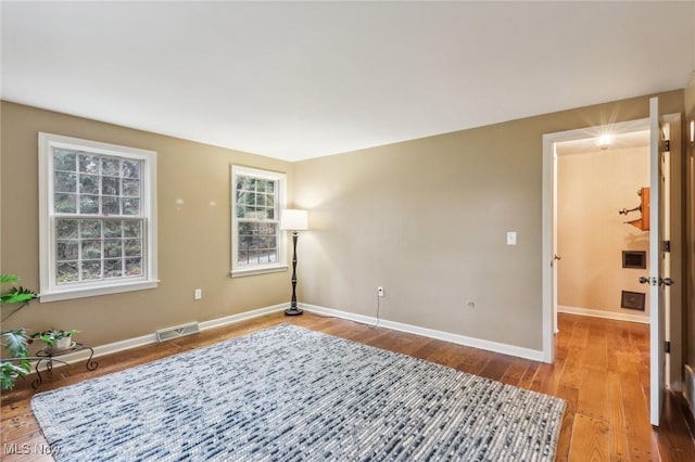 empty room featuring visible vents, baseboards, and wood finished floors