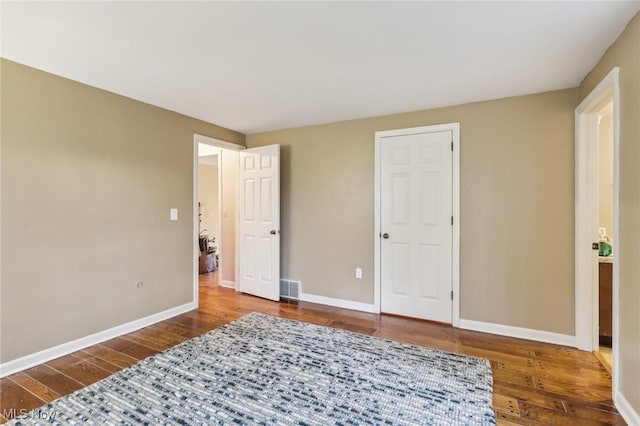 bedroom with wood finished floors, baseboards, and visible vents