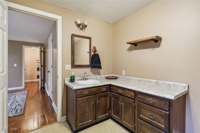 bathroom with vanity, wood finished floors, and baseboards