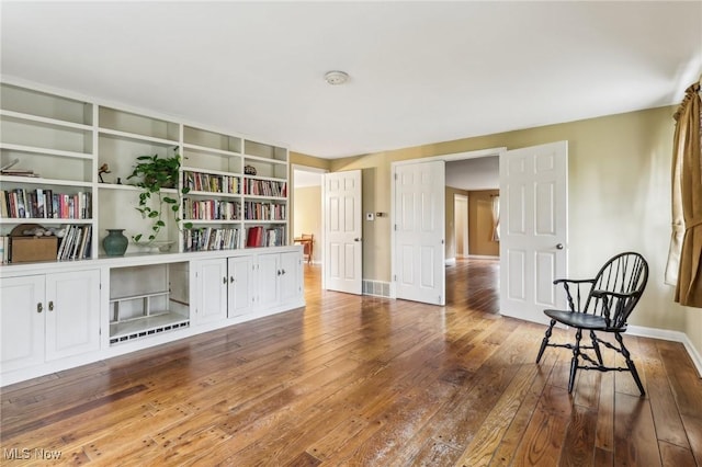 sitting room featuring built in features, visible vents, baseboards, and hardwood / wood-style flooring