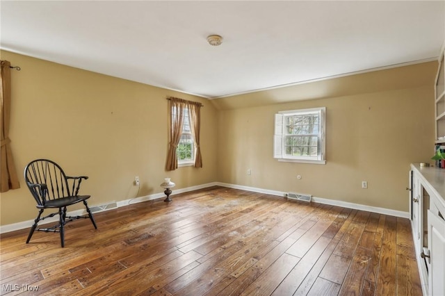 sitting room with vaulted ceiling, visible vents, a healthy amount of sunlight, and hardwood / wood-style floors