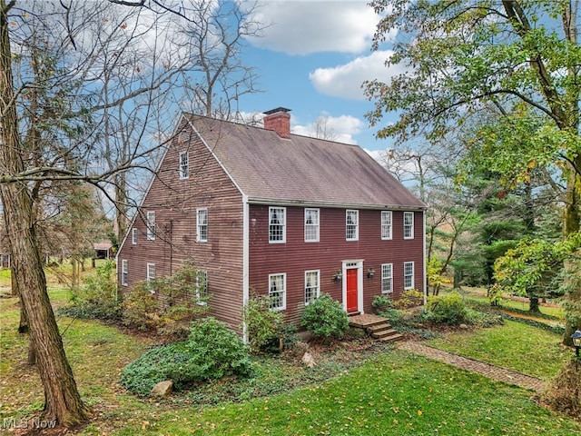 view of front of property with a chimney, a front lawn, and roof with shingles