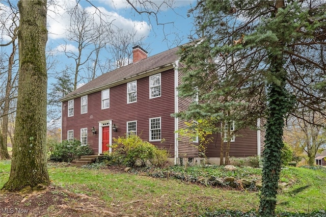 colonial home with a shingled roof and a chimney