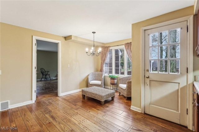 sitting room with hardwood / wood-style floors, an inviting chandelier, baseboards, and visible vents