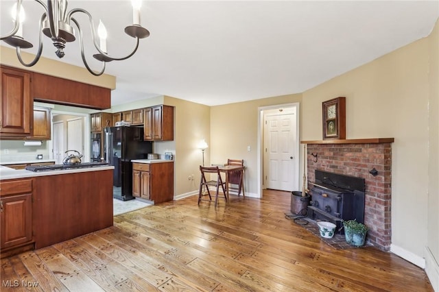 kitchen featuring brown cabinetry, baseboards, freestanding refrigerator, and light wood-style floors