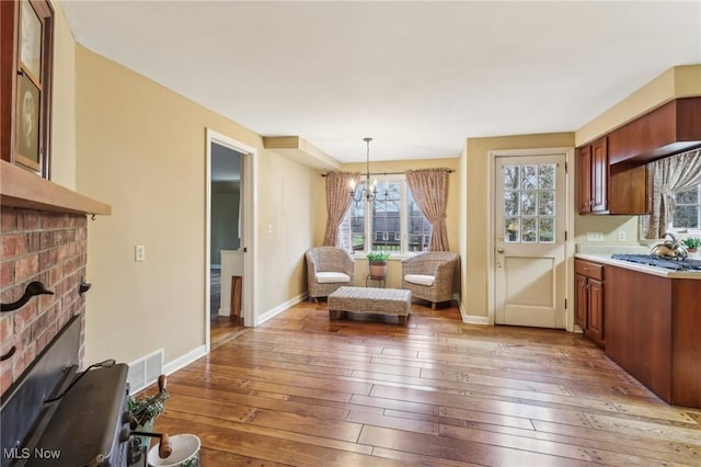 living area with visible vents, baseboards, light wood finished floors, a fireplace, and a chandelier