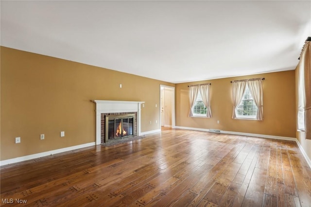 unfurnished living room with a fireplace, baseboards, and wood-type flooring