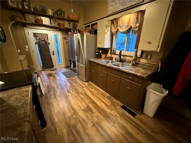 kitchen featuring light wood-type flooring, dark brown cabinets, sink, white cabinets, and stainless steel fridge with ice dispenser