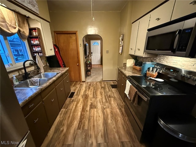 kitchen with appliances with stainless steel finishes, tasteful backsplash, sink, light hardwood / wood-style flooring, and white cabinets