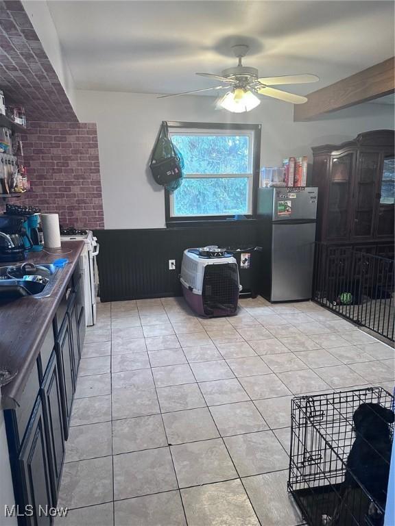 2908 Columbus Ave, Ashtabula, OH 44004 - kitchen featuring freestanding refrigerator, a ceiling fan, light tile patterned flooring, dark countertops, and white gas range oven