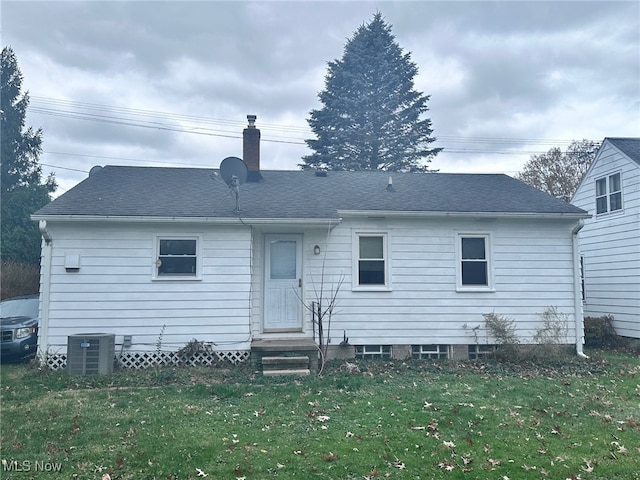 rear view of property featuring cooling unit and a lawn