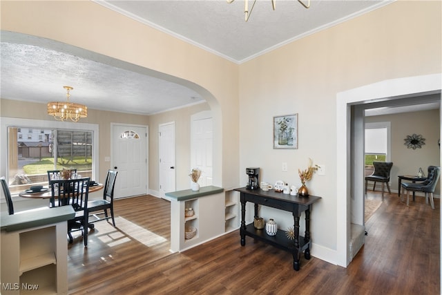 foyer entrance featuring a chandelier, a textured ceiling, dark hardwood / wood-style flooring, and ornamental molding