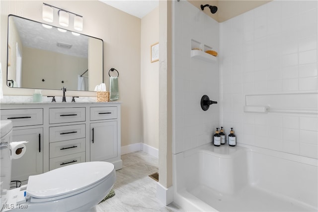 bathroom with a tile shower, vanity, and toilet