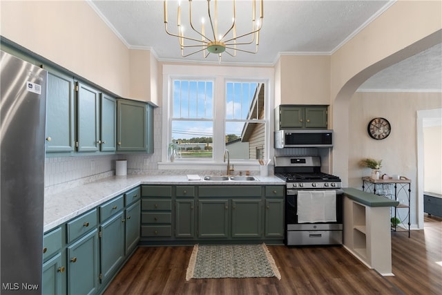 kitchen with sink, dark wood-type flooring, crown molding, decorative light fixtures, and appliances with stainless steel finishes