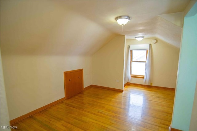 additional living space featuring vaulted ceiling and light hardwood / wood-style floors