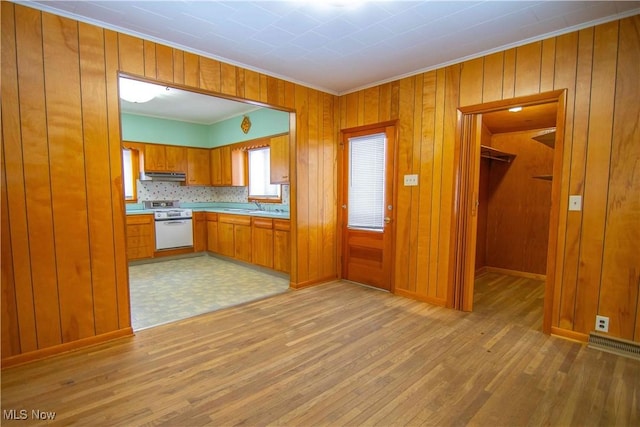 kitchen featuring wooden walls, light hardwood / wood-style floors, and white stove