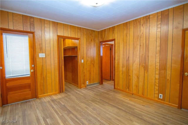 foyer with light wood-type flooring and wood walls