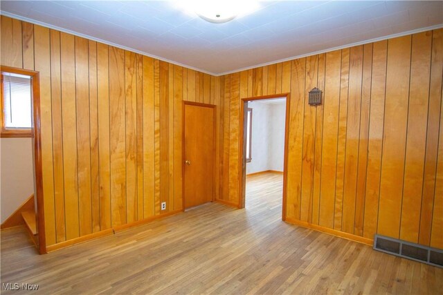 spare room with light hardwood / wood-style flooring and wood walls