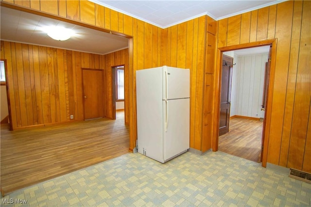 kitchen featuring white refrigerator, crown molding, and wooden walls