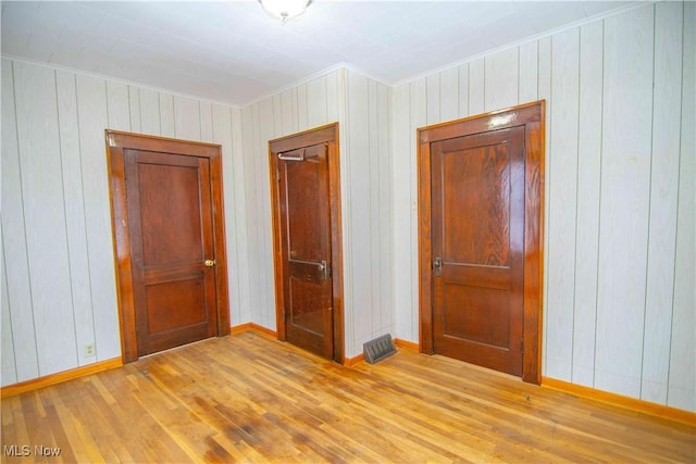 unfurnished bedroom featuring crown molding and light wood-type flooring