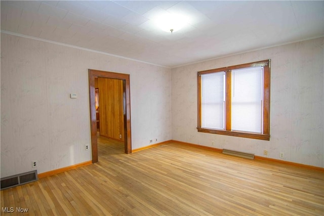 empty room with crown molding and light wood-type flooring