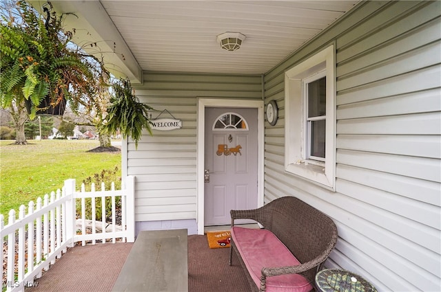 doorway to property featuring a lawn and covered porch