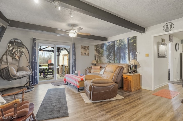 living room with ceiling fan, beamed ceiling, light hardwood / wood-style floors, and a textured ceiling