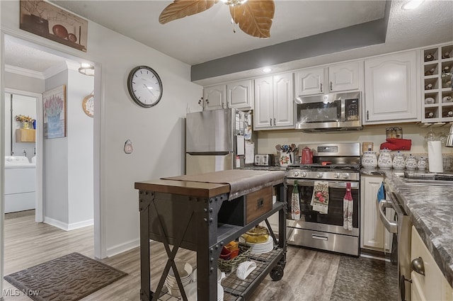 kitchen with stainless steel appliances, crown molding, hardwood / wood-style floors, washer / clothes dryer, and white cabinetry