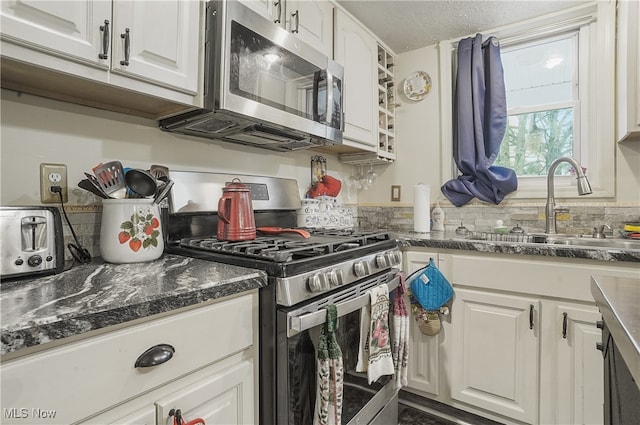 kitchen with sink, a textured ceiling, tasteful backsplash, white cabinetry, and stainless steel appliances