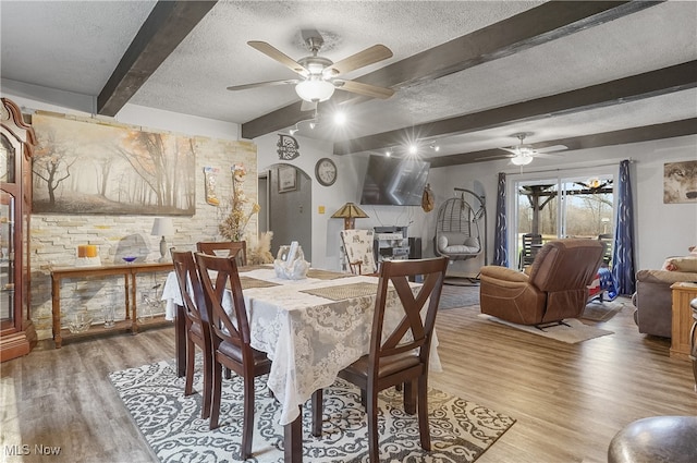 dining area with beamed ceiling, a textured ceiling, and hardwood / wood-style flooring