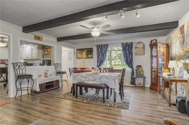 dining room featuring beamed ceiling, a textured ceiling, dark hardwood / wood-style floors, and ceiling fan