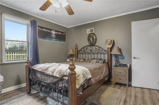 bedroom with ceiling fan, dark wood-type flooring, a textured ceiling, and ornamental molding