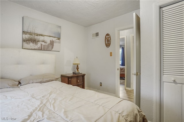 bedroom featuring a textured ceiling and hardwood / wood-style flooring