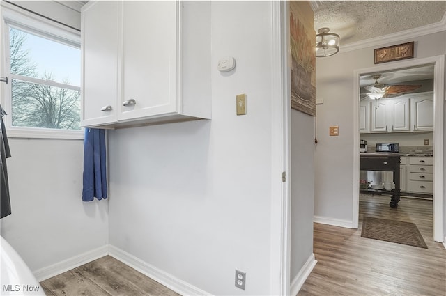 bathroom featuring ceiling fan, wood-type flooring, a textured ceiling, and ornamental molding