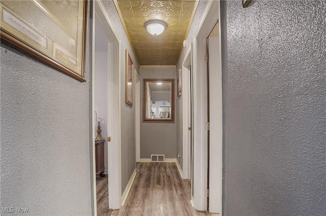 hallway with hardwood / wood-style floors and ornamental molding