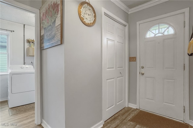 foyer entrance featuring washer / clothes dryer, crown molding, a healthy amount of sunlight, and light hardwood / wood-style floors