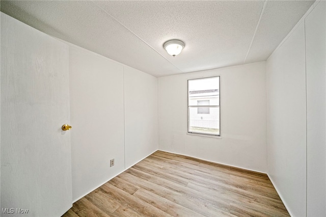 spare room with light hardwood / wood-style floors and a textured ceiling