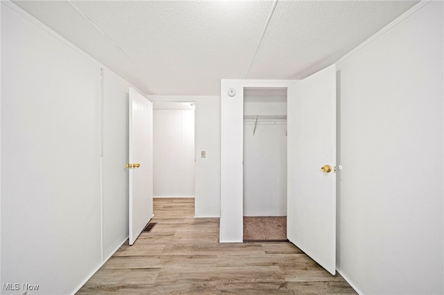 unfurnished bedroom featuring a closet, light hardwood / wood-style floors, and a textured ceiling