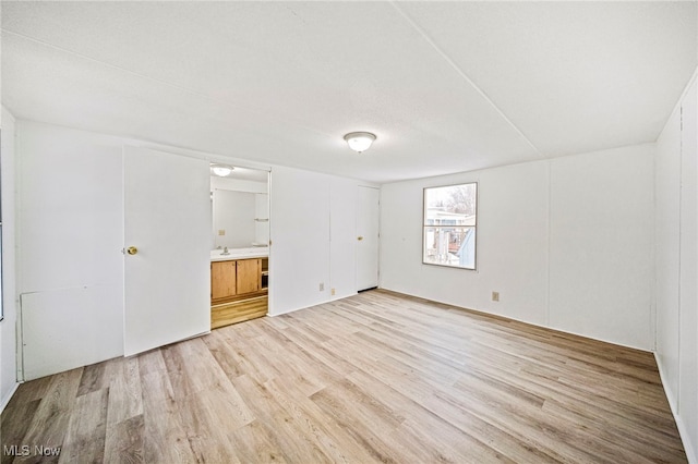 unfurnished bedroom with ensuite bath, sink, and light wood-type flooring