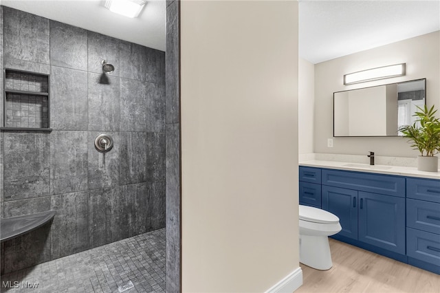 bathroom featuring tiled shower, hardwood / wood-style floors, vanity, and toilet