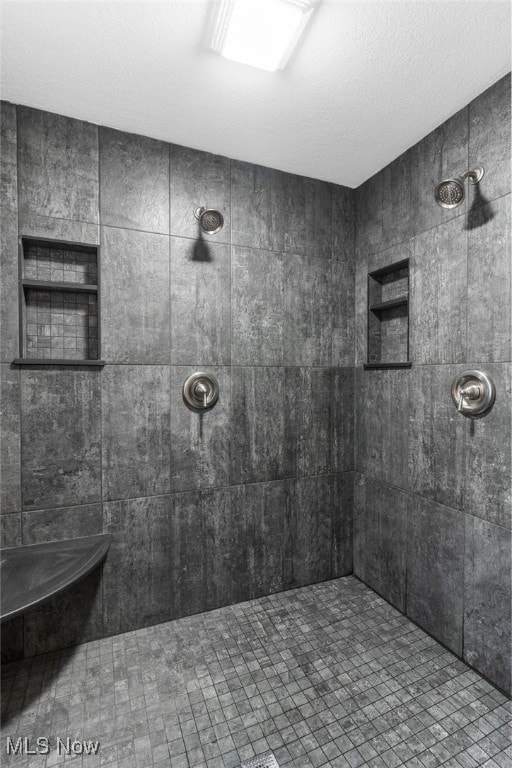 bathroom with a tile shower and a textured ceiling