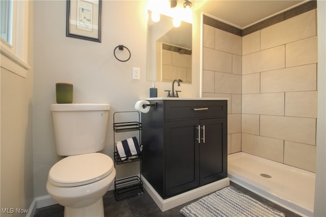 bathroom with tiled shower, vanity, and toilet