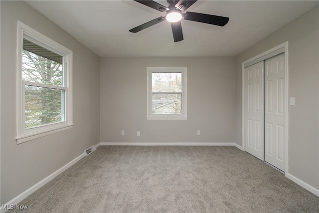 unfurnished bedroom with light carpet, multiple windows, and ceiling fan