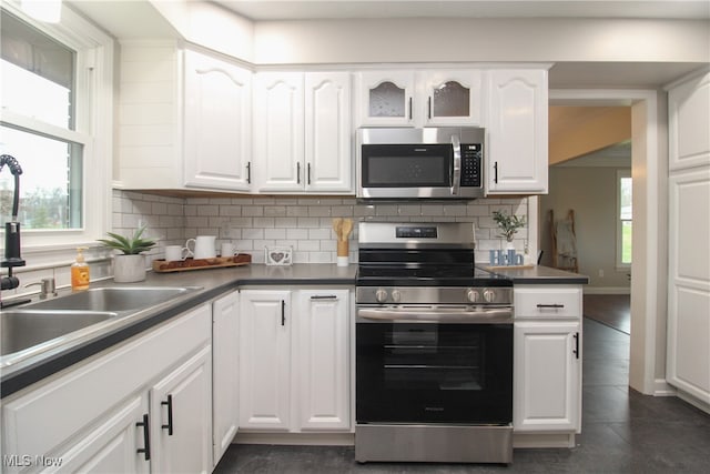 kitchen featuring white cabinets, appliances with stainless steel finishes, decorative backsplash, and sink