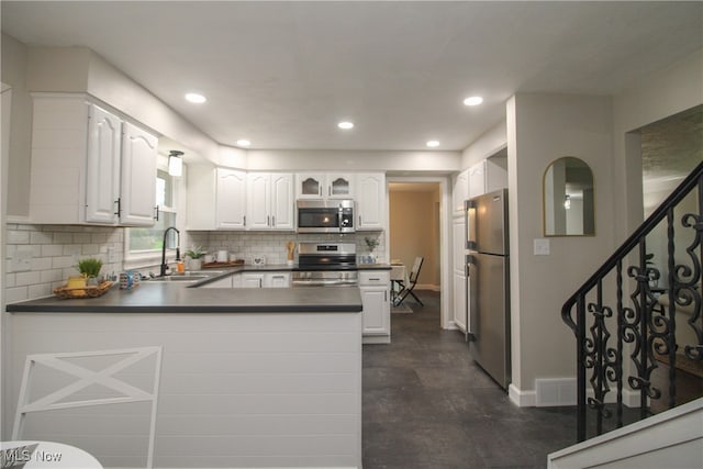 kitchen with backsplash, sink, white cabinetry, kitchen peninsula, and stainless steel appliances