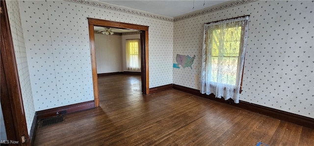 empty room featuring dark hardwood / wood-style floors, a healthy amount of sunlight, and ornamental molding