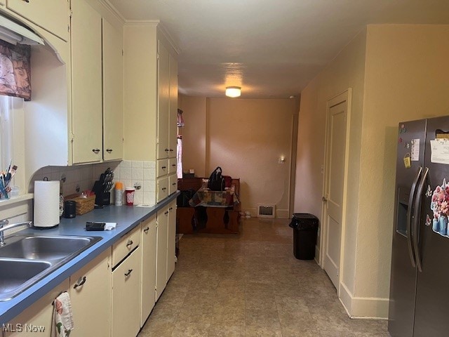 kitchen with decorative backsplash, stainless steel fridge with ice dispenser, white cabinetry, and sink