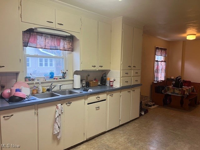 kitchen with backsplash, sink, and white cabinets